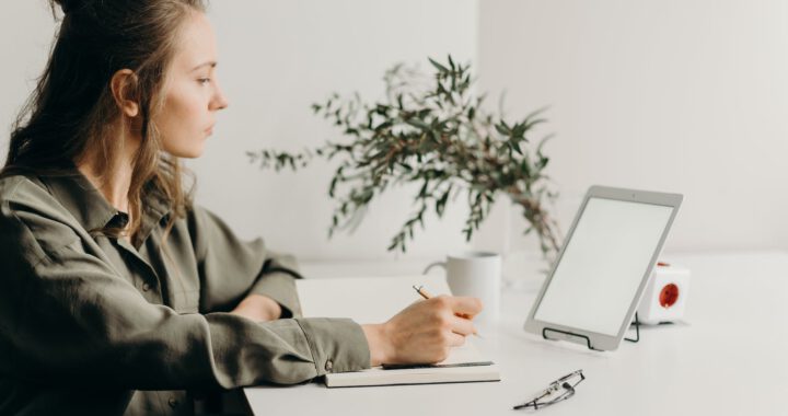 woman in gray coat using white laptop computer